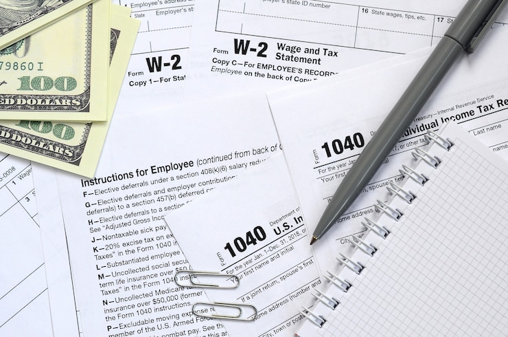 Photo the pen, notebook and dollar bills is lies on the tax form 1040 u.s. individual income tax return