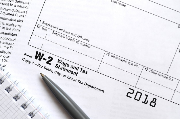 The pen and notebook on the tax form W-2 Wage and Tax Statement. The time to pay taxes