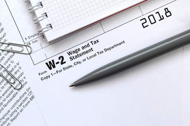 The pen and notebook on the tax form W-2 Wage and Tax Statement. The time to pay taxes