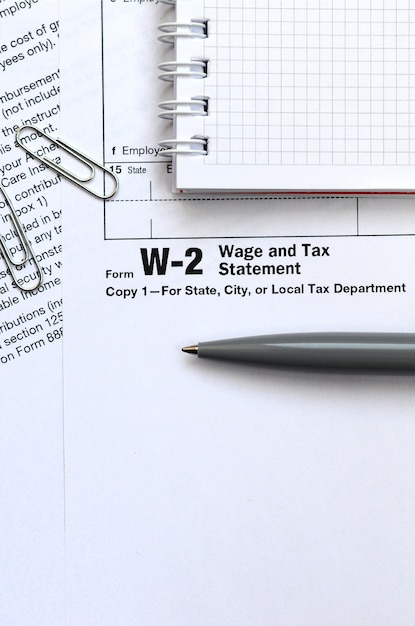 The pen and notebook on the tax form W-2 Wage and Tax Statement. The time to pay taxes