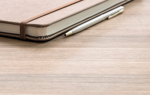 Pen and notebook up close on a  wooden desk