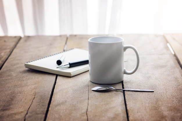 Pen on notebook with coffee cup on wooden