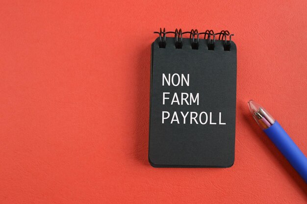 Pen and notebook written with text non farm payroll