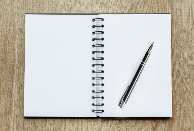 Pen and Notepad on the wooden desk. Business concept, blank sheet