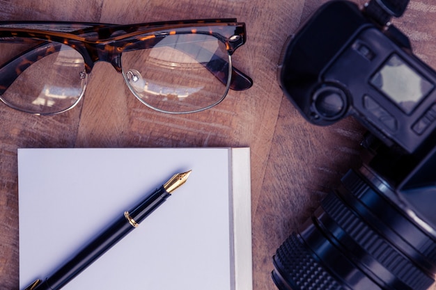 Pen op papier door camera en bril aan tafel in creatief kantoor