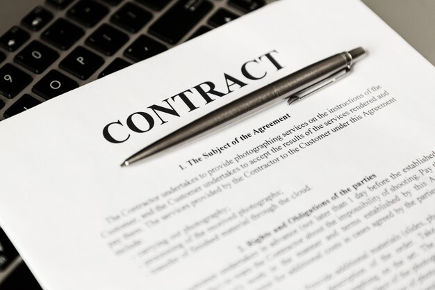 Ручка для подписания контракта. Ручка и контракт лежат на ноутбуке.