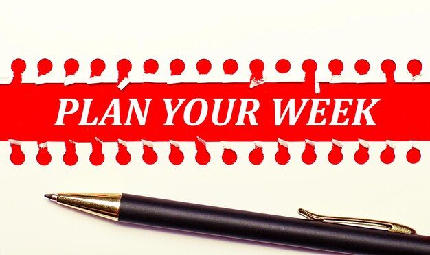 明るい赤の背景にペンと白の破れた紙のストリップとテキストPLANYOUR WEEK