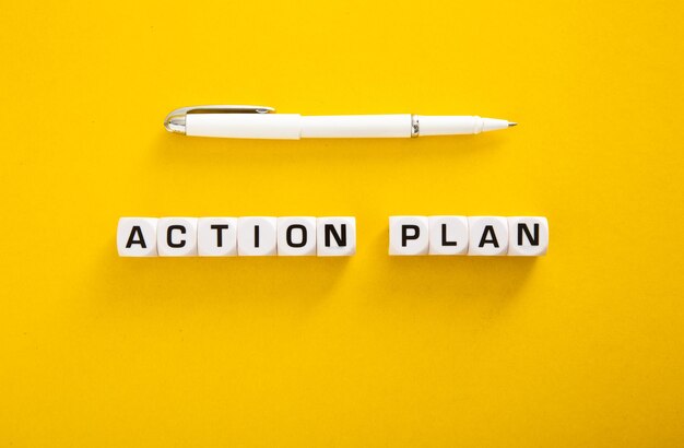 Pen with action plan word over yellow background