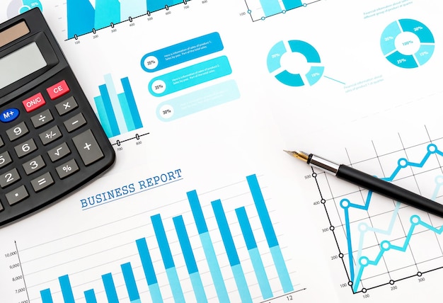 Pen with calculator on the financial graphs Business concept Top view