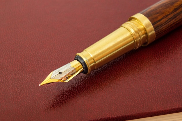 Pen with a gold plated pen on brown notepad for notes close up