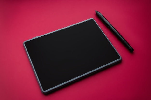 Pen with a graphic tablet on red background, close-up. Gadget for art and work.