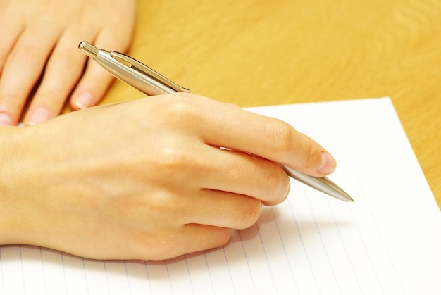 Pen in woman hand isolated on wood background