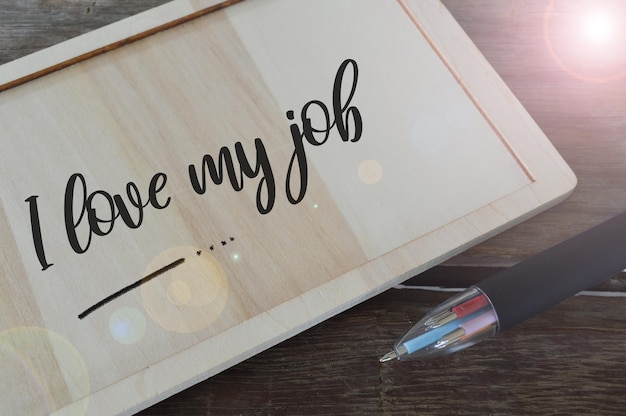 Pen and wooden board written with text I LOVE MY JOB Selective focus