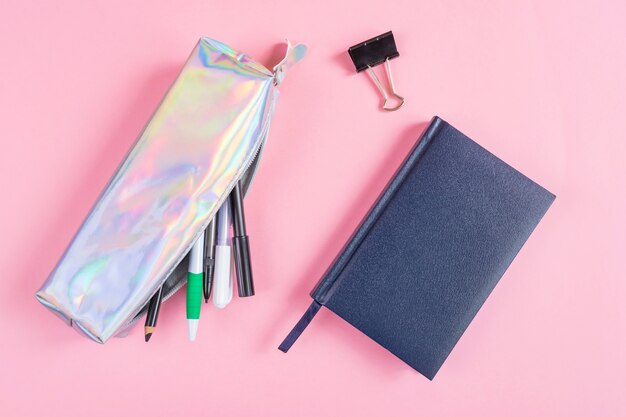 Photo pencil case with pens and pencils, notebook on a pink .