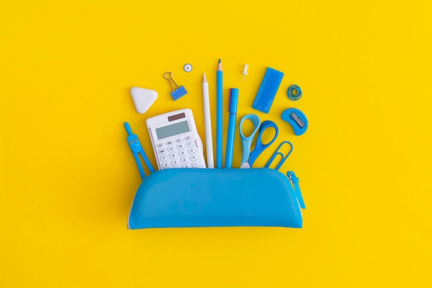 Pencil case with school stationery on a yellow background