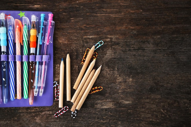 Pencil case with various stationery on old wooden table