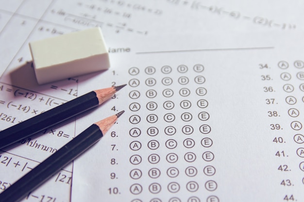 Pencil and eraser on answer sheets or Standardized test form with answers bubbled. multiple choice answer sheet