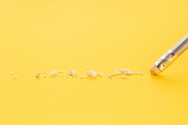 Pencil eraser working on yellow paper background Mistake erasing or correction concept Copy space