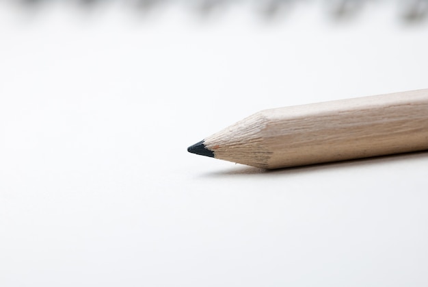 A pencil is placed on a notebook with a white background