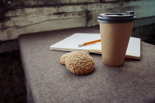 Pencil, notebook and paper coffee cup on a brown fabric background