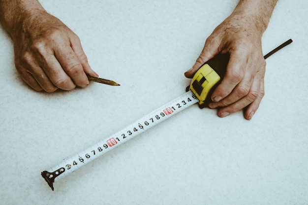 Photo pencil and roulette in hands of elderly working man