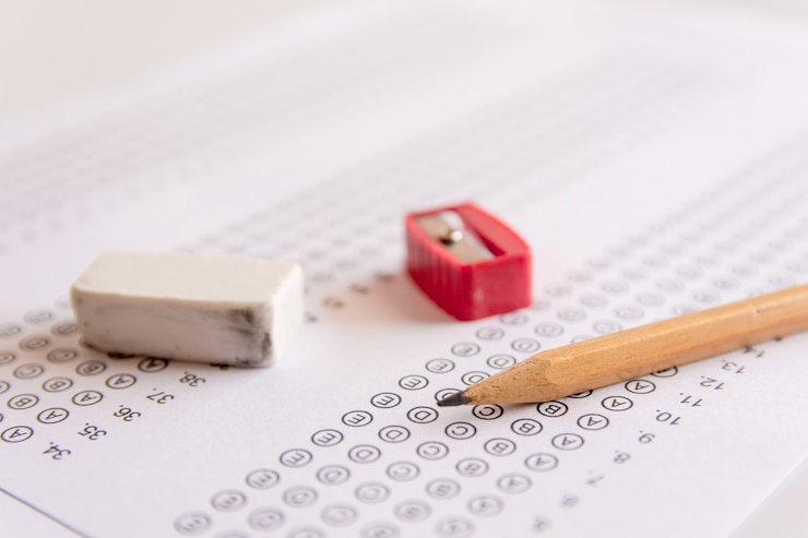 Photo pencil, sharpener and eraser on answer sheets or standardized test form 