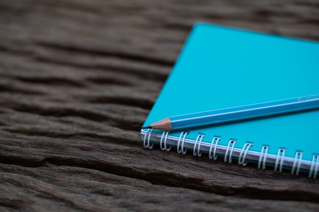 Pencil on top of book mockup on the old wood desk at the background,