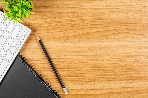 Pencil with a computer keyboard and notebook on wooden desk