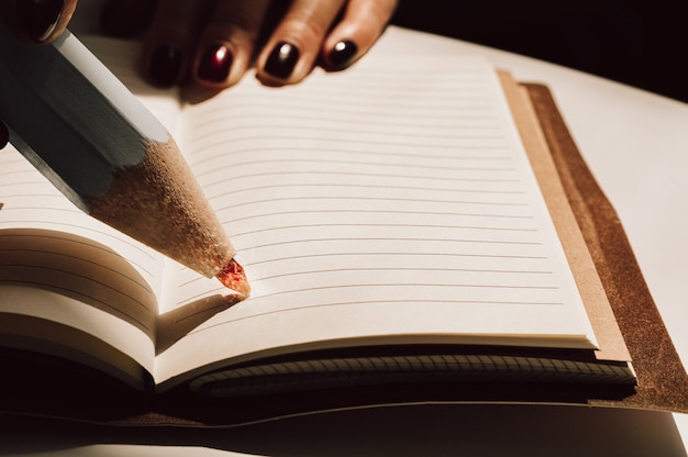 Pencil with a fire stylus is on a sheet of a notebook.