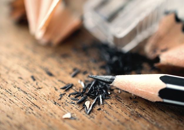 Pencil with sharpening shavings, on wooden table..