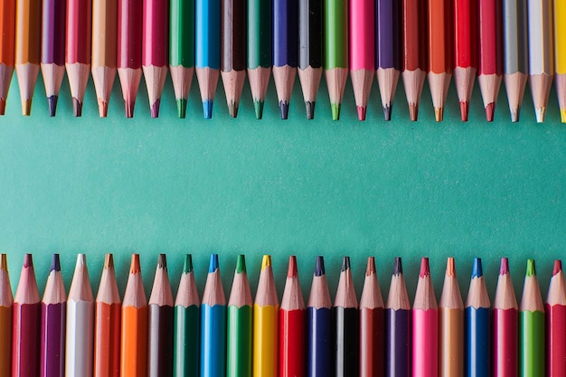 Pencils of different sizes on green background