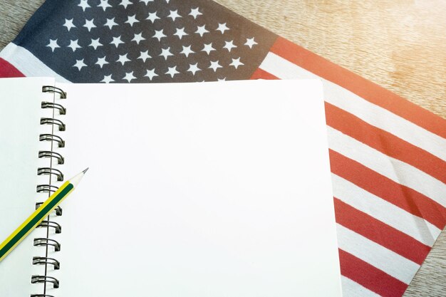 Photo pencils notebooks and american flags on a wooden table international business concept