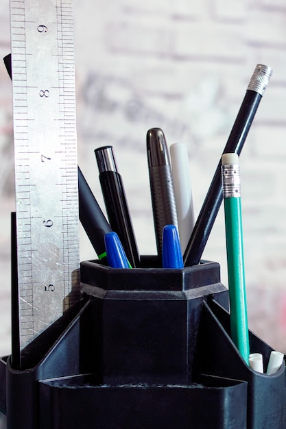 Карандаши и ручки в подставке на столе