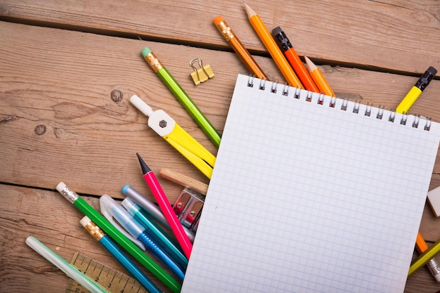 Pencils and pens student with a notebook on a wooden surface