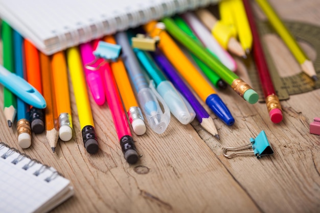 Pencils and pens student with a notebook on a wooden surface