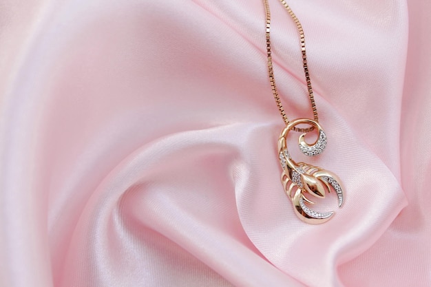 Pendant in the form of a scorpion on a pink silk background