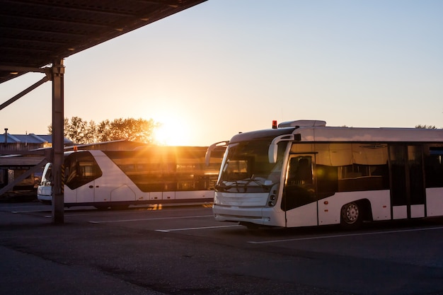 Pendelbussen op de parkeerplaats van de luchthaven in de stralen van de ondergaande zon