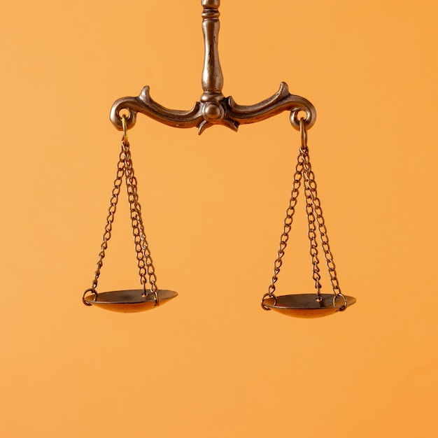 Pendulum scales over an orange background with copy space in a concept of law enforcement and justice