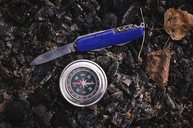 Photo penknife and a compass on the coals an extinguished campfire picnic recreation and adventures in wild