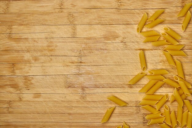 Penne pasta on dark wooden surface.