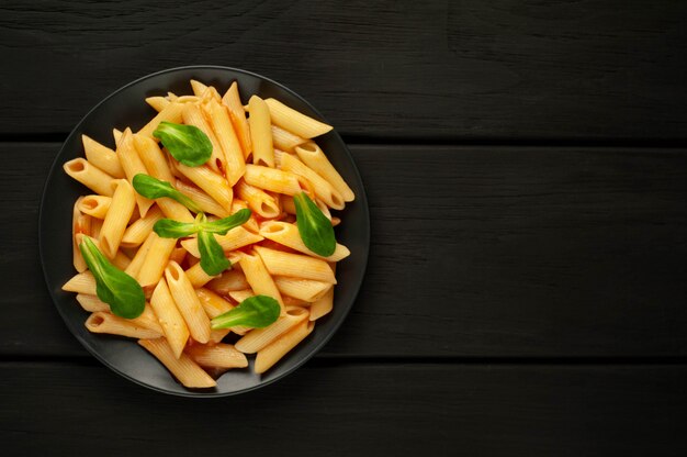 Penne pasta in plate on wood background