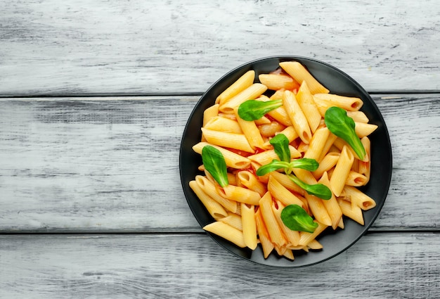 Penne pasta in plate on wood background