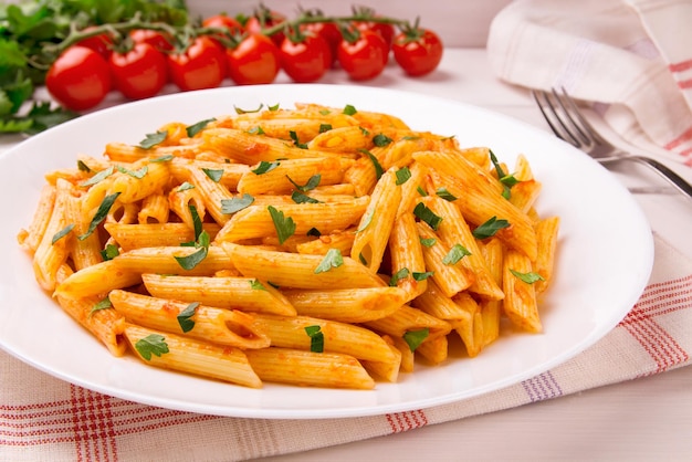 Penne pasta in tomato sauce decorated with parsley on a white wooden table very tasty