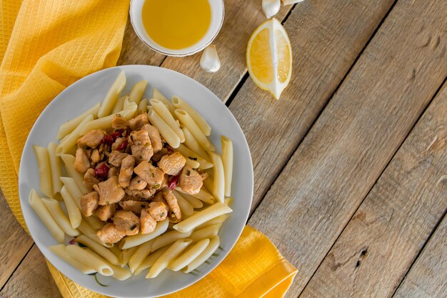 Penne pasta with appetizing chicken in a creamy sauce on a light wooden background