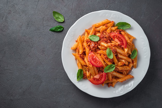 Premium Photo | Penne pasta with bolognese sauce and basil in a white ...