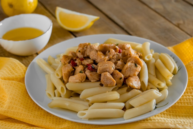 Penne pasta with  chicken in a creamy sauce on a light wooden background.