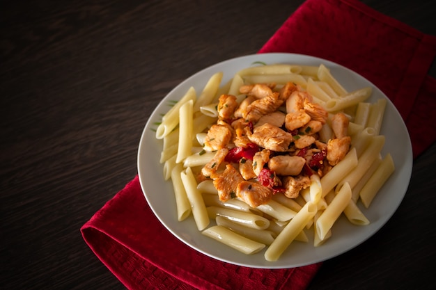 Penne pasta with chicken and vegetables in tomato sauce