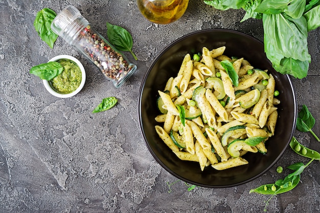 Penne pasta with  pesto sauce, zucchini, green peas and basil. Italian food.