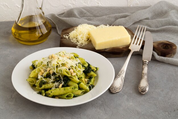 Penne pasta with spinach on grey background.