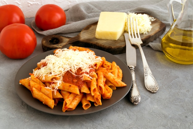 Pasta di penne con salsa di pomodoro su sfondo grigio.